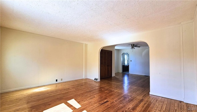 spare room with arched walkways, a textured ceiling, and hardwood / wood-style flooring