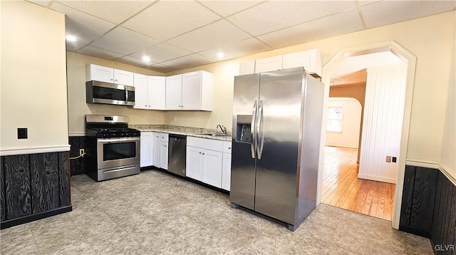 kitchen featuring white cabinets, a drop ceiling, appliances with stainless steel finishes, and a sink