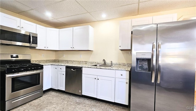 kitchen with a sink, a drop ceiling, appliances with stainless steel finishes, and white cabinets