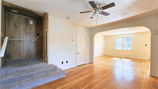 unfurnished room with arched walkways, a textured ceiling, ceiling fan, and hardwood / wood-style flooring