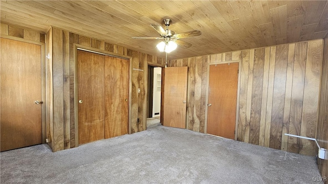 unfurnished bedroom featuring carpet flooring, wood walls, wood ceiling, and a ceiling fan