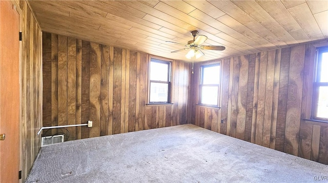 spare room with wooden ceiling, wooden walls, and a ceiling fan