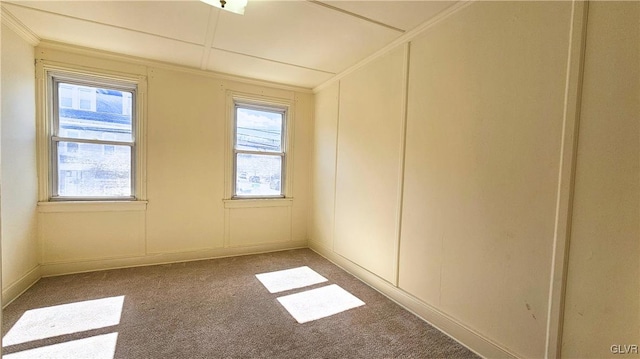 unfurnished room with carpet floors, crown molding, and a decorative wall