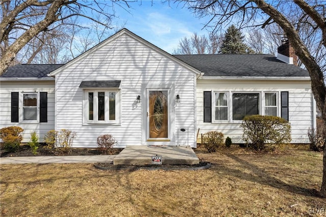 view of front of home featuring a front lawn, roof with shingles, and a chimney