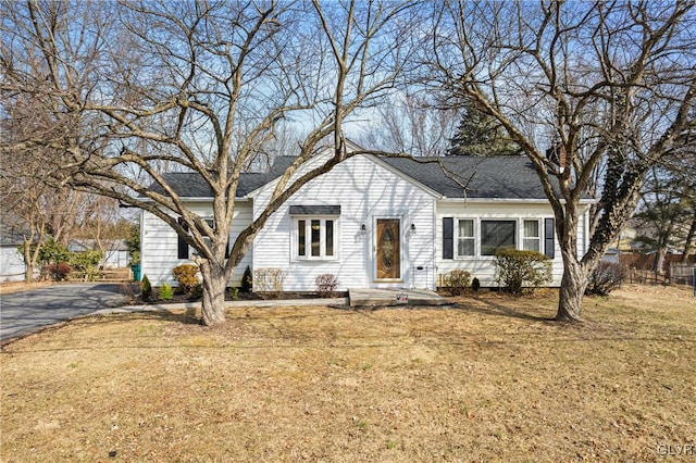 view of front of home featuring driveway, roof with shingles, and a front lawn