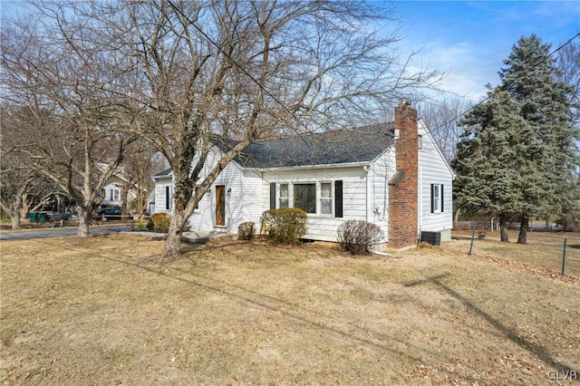 view of front facade with central AC, a chimney, and a front lawn