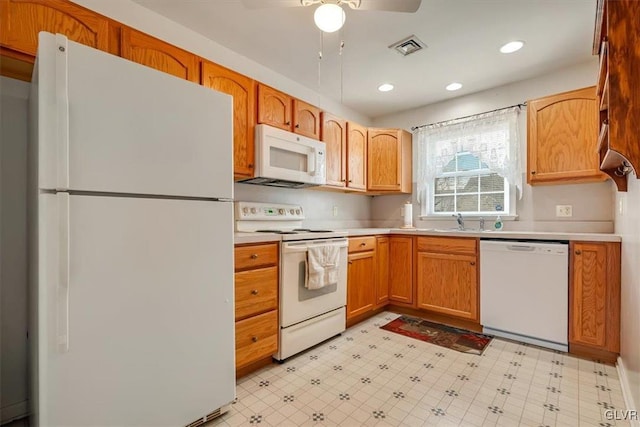 kitchen featuring white appliances, light floors, visible vents, and a sink