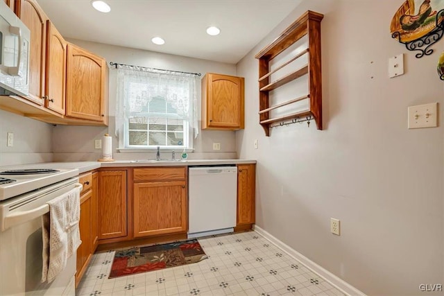 kitchen featuring a sink, white appliances, light countertops, baseboards, and light floors