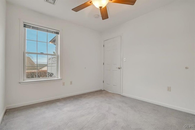 empty room featuring light carpet, a ceiling fan, and baseboards