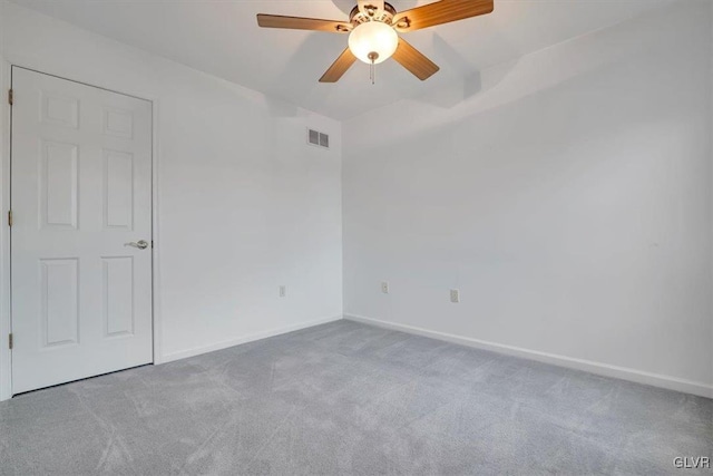 carpeted spare room featuring visible vents, baseboards, and a ceiling fan