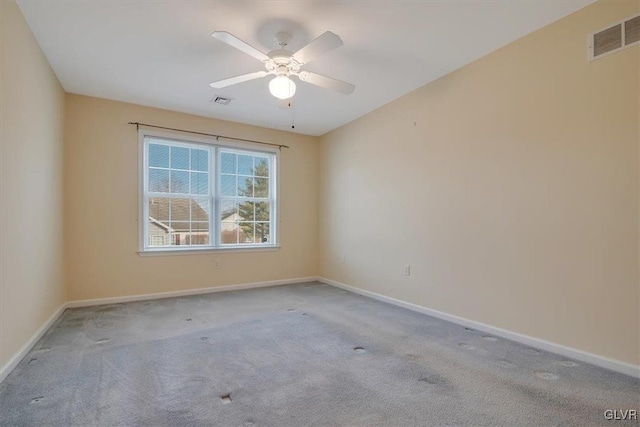 carpeted spare room featuring visible vents, ceiling fan, and baseboards