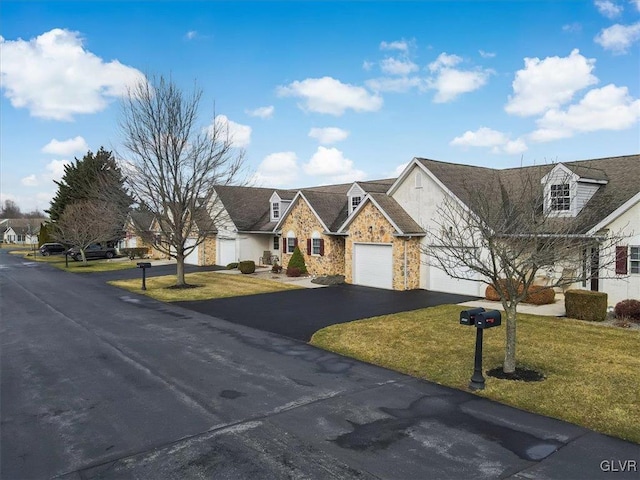 view of front of home with aphalt driveway, a residential view, a front yard, stone siding, and an attached garage