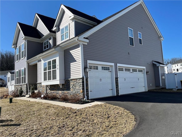 view of side of property with stone siding, driveway, and a garage