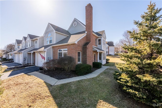 view of property exterior featuring an attached garage, brick siding, a residential view, and a chimney