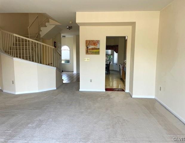 unfurnished room with stairway, baseboards, and carpet flooring