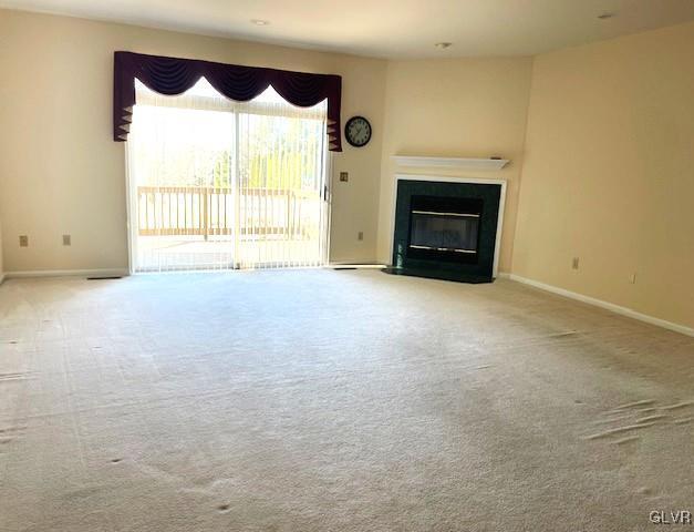 unfurnished living room with a fireplace with flush hearth, carpet flooring, and baseboards