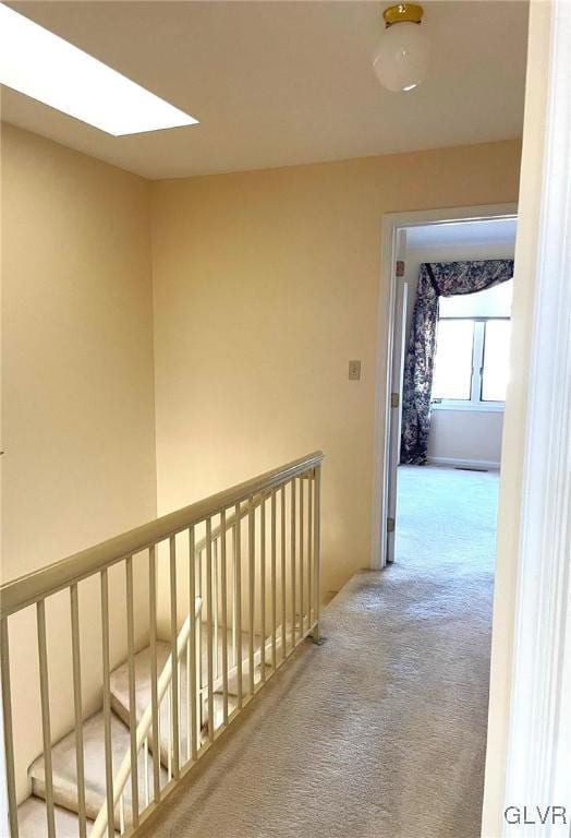 hallway with carpet floors and a skylight