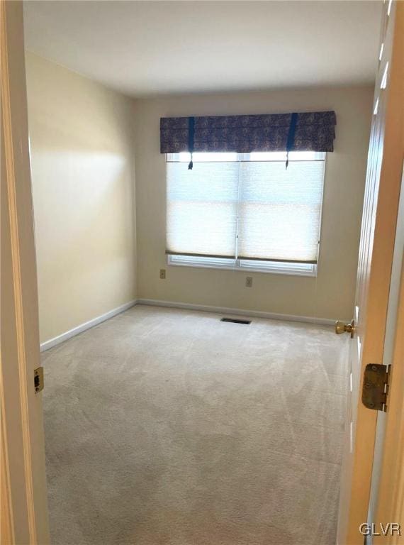 unfurnished room with carpet flooring, baseboards, visible vents, and a wealth of natural light