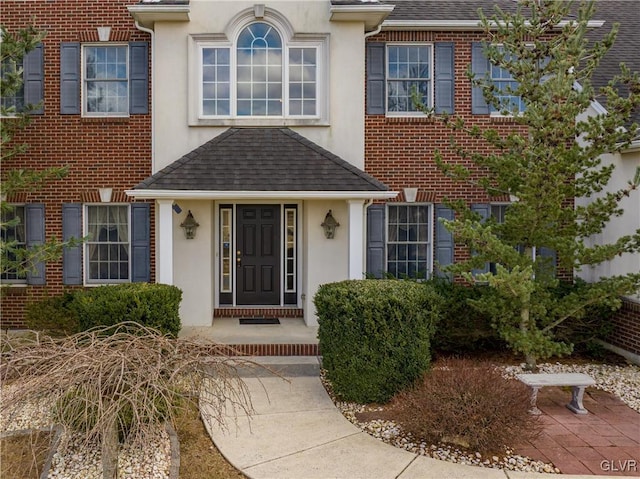 doorway to property with stucco siding and roof with shingles