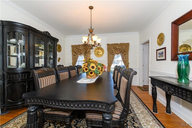 dining space with an inviting chandelier, wood finished floors, and ornamental molding