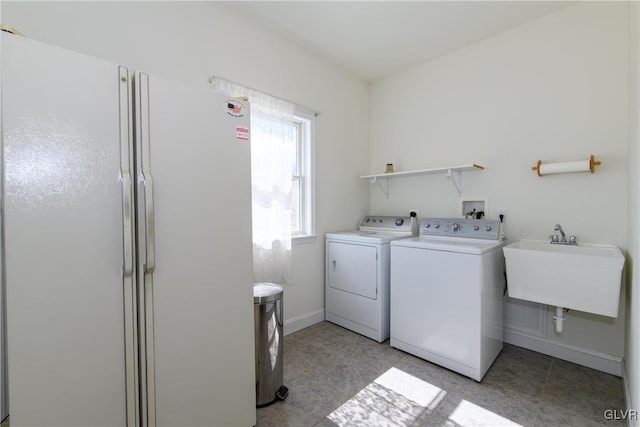 washroom with laundry area, washing machine and dryer, baseboards, and a sink