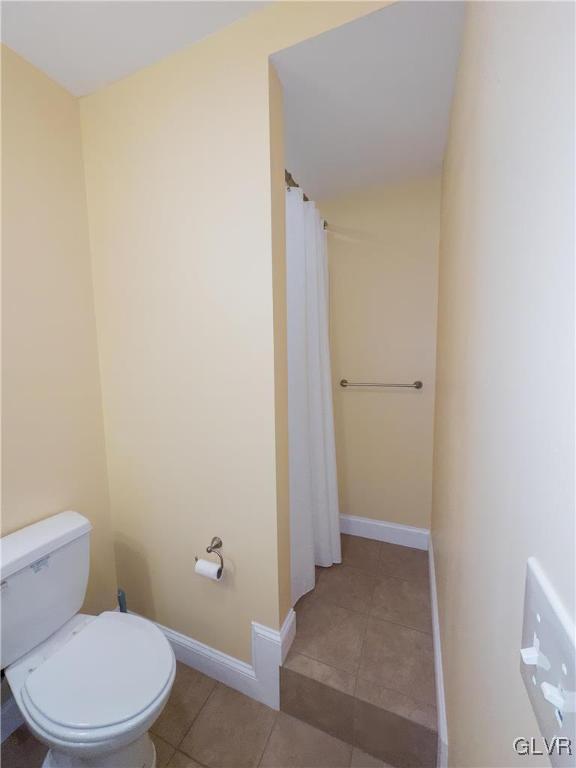 bathroom with a shower with shower curtain, baseboards, toilet, and tile patterned flooring