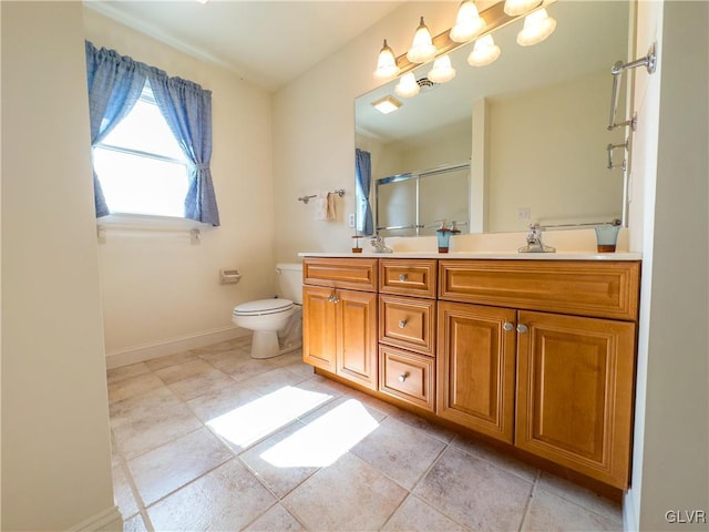 full bath featuring baseboards, double vanity, a stall shower, a sink, and toilet