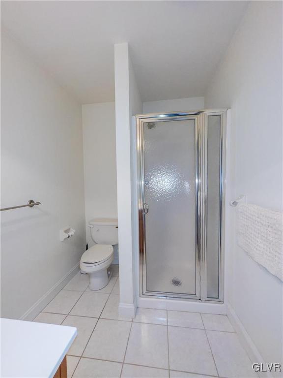 full bath featuring tile patterned floors, a stall shower, toilet, and baseboards