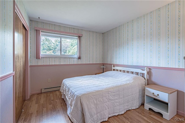 bedroom featuring baseboard heating, wallpapered walls, and a wainscoted wall