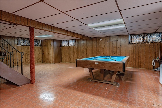 recreation room with tile patterned floors, a paneled ceiling, and wood walls