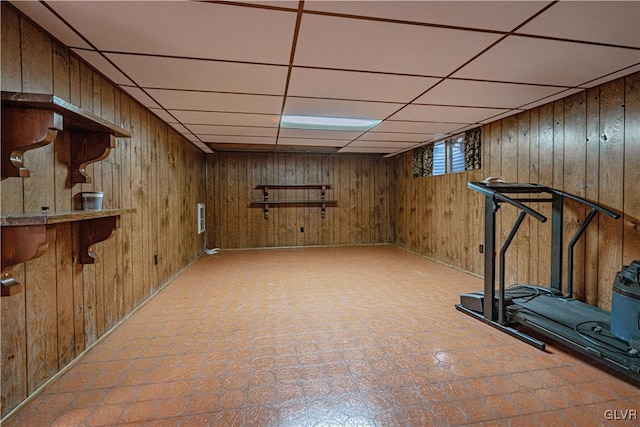 workout area featuring tile patterned floors, a drop ceiling, and wood walls