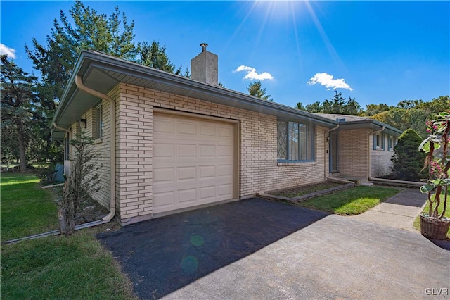 ranch-style house with brick siding, a front lawn, aphalt driveway, a chimney, and an attached garage