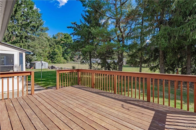 deck featuring a storage shed, a yard, and an outbuilding