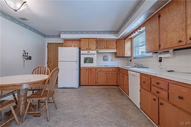 kitchen featuring white appliances, light countertops, backsplash, and a sink