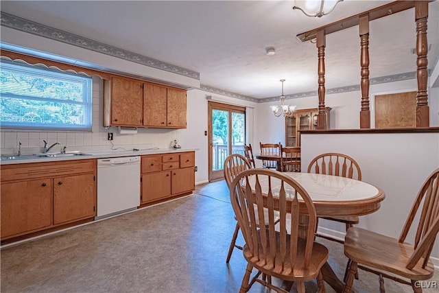 kitchen with a sink, light countertops, dishwasher, backsplash, and a chandelier