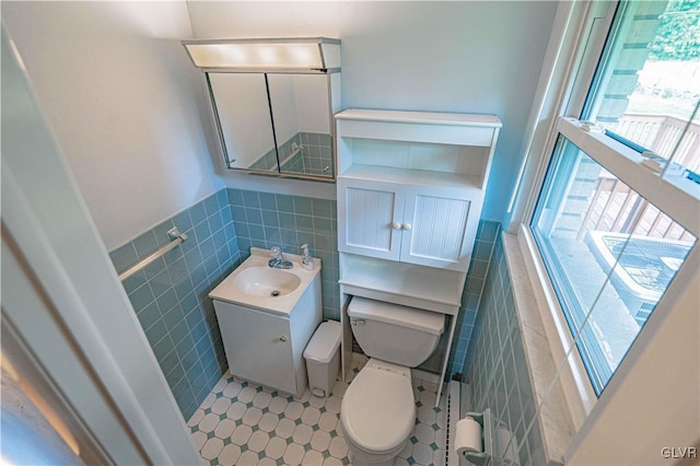 bathroom with vanity, tile walls, toilet, and a wainscoted wall