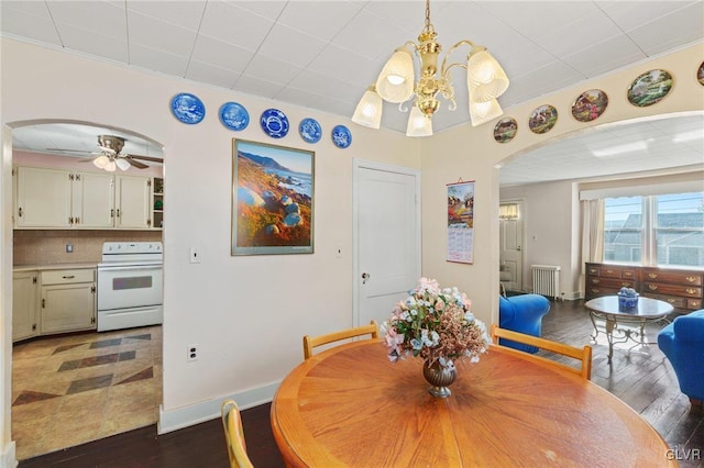 dining room with arched walkways, radiator heating unit, dark wood-type flooring, and baseboards