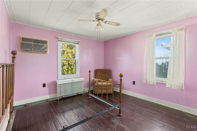 bedroom featuring radiator, baseboards, ceiling fan, a wall mounted air conditioner, and wood-type flooring