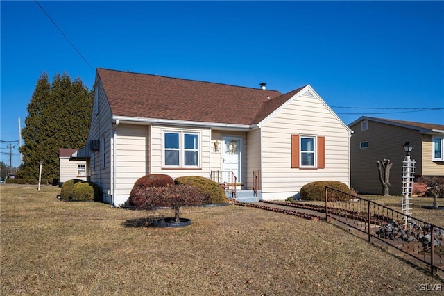 view of front of house with a front yard and a shingled roof