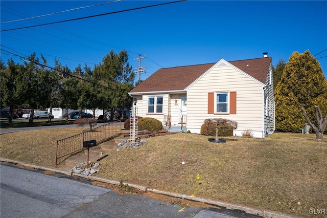 view of front of property with a front lawn and a shingled roof