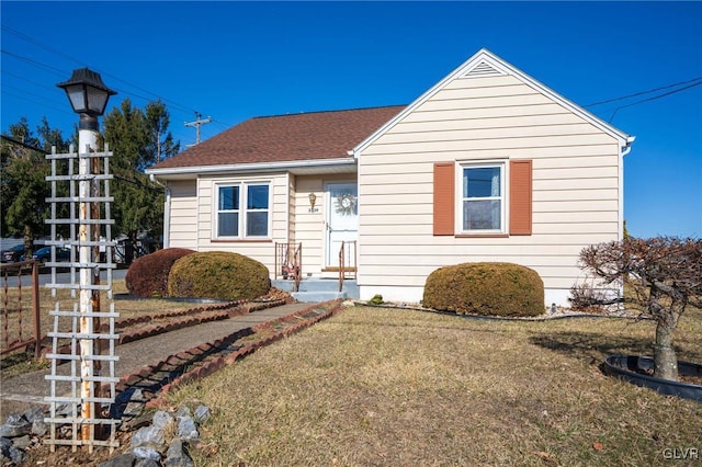 view of front of property with a shingled roof and a front lawn