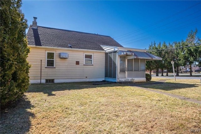 rear view of property with a chimney, a lawn, and a shingled roof