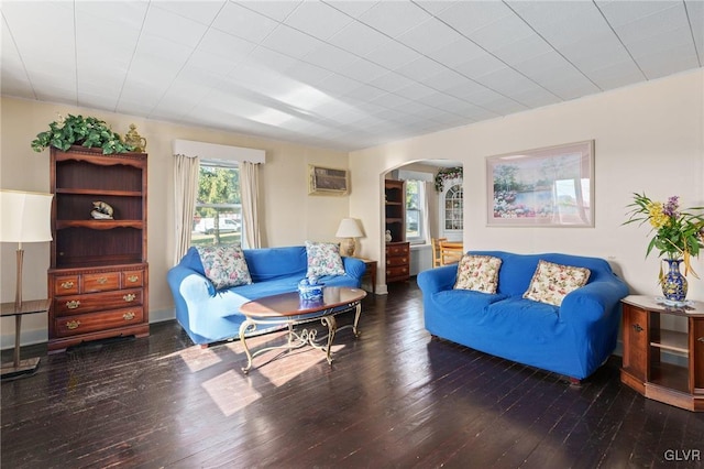 living area featuring arched walkways, a wall mounted AC, and hardwood / wood-style flooring