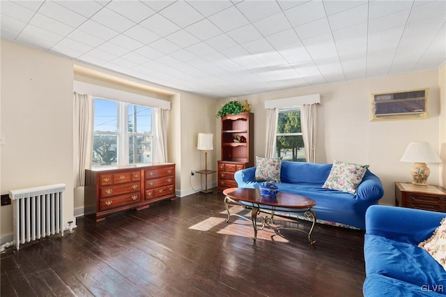 sitting room featuring a wall mounted AC, radiator heating unit, baseboards, and hardwood / wood-style flooring