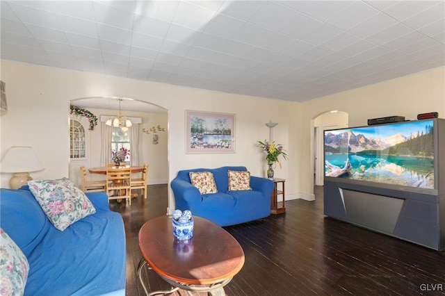 living area with baseboards, arched walkways, and wood finished floors