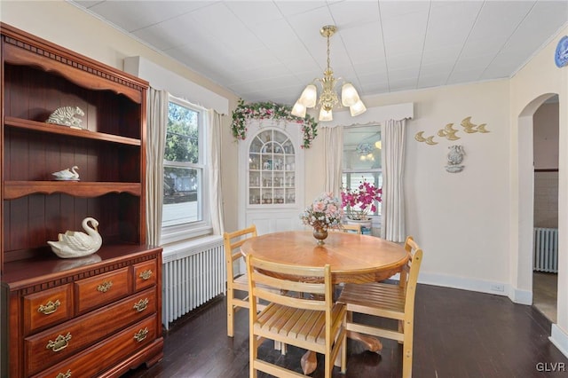 dining area featuring arched walkways, an inviting chandelier, radiator heating unit, and dark wood-type flooring