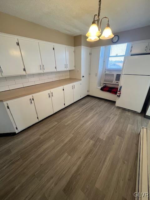 kitchen featuring dark wood-type flooring, pendant lighting, freestanding refrigerator, white cabinets, and light countertops