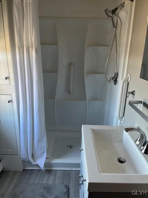 bathroom with a shower stall, vanity, and wood finished floors