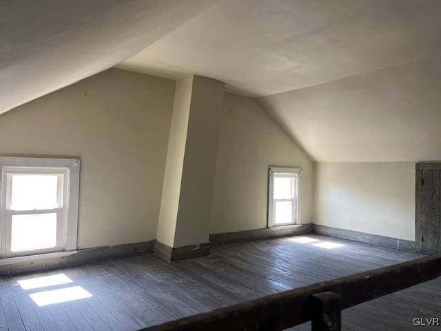 additional living space with baseboards, hardwood / wood-style floors, and vaulted ceiling