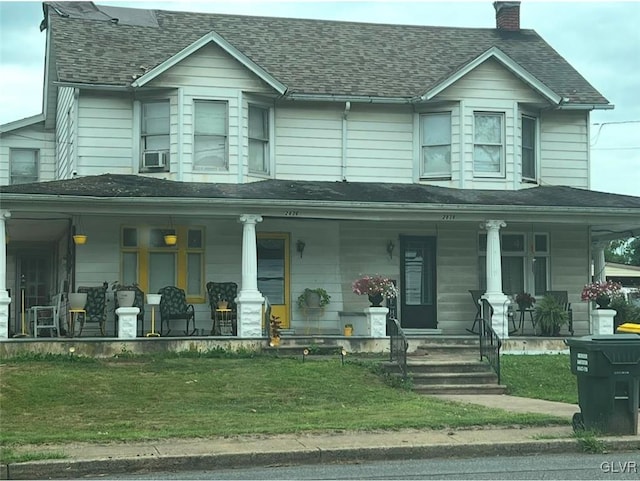 view of front of house featuring a shingled roof, a porch, a front lawn, and a chimney